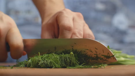 Closeup-of-cutting-green-dill-on-a-board-in-the-kitchen-on-a-wooden-board.-cutting-grass-and-greenery